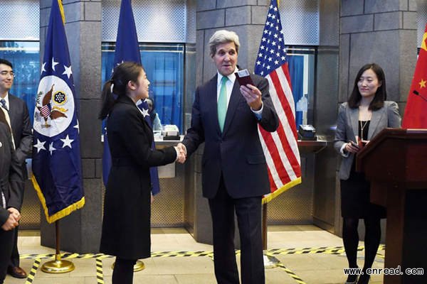 US Secretary of State John Kerry (centre R) prepares to give a visa to a Chinese woman at a press conference at the US Embassy in Beijing on November 12, 2014. US President Barack Obama announced on November 10, a deal to extend visas for Chinese nationals going to the US to work or study.