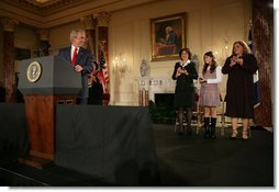 President George W. Bush acknowledges his guests, from left to right, Yamile Llanes Labrada, Melissa Gonzalez, and Marlenis Gonzalez during his remarks on Cuba policy, Wednesday, October 24, 2007, at the State Department in Washington, D.C. Labrada is the wife of Jorge Luis Garcia Paneque, a surgeon and journalist who was sentenced to 24 years in prison for speaking out against the regime. Melissa's father, Jorge Luis Gonzalez Tanquero is currently being held in a Cuban prison after being arrested for crimes against the state. White House photo by Eric Draper