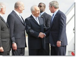 President George W. Bush is greeted by Israels President Shimon Peres, center, and Prime Minister Ehud Olmert after arriving in Tel Aviv Wednesday, Jan. 9, 2008, for a weeklong visit to the Mideast.  White House photo by Eric Draper