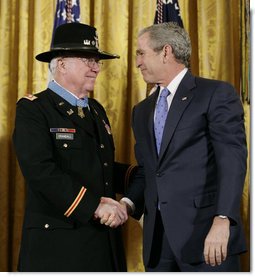 President George W. Bush shakes hands with U.S. Army Major Bruce P. Crandall after awarding Crandall the Medal of Honor in a ceremony in the East Room of the White House, Monday, Feb. 26, 2007, for his extraordinary heroism as a 1st Cavalry helicopter flight commander, completing 22 flights under intense enemy fire to aid troops in the Republic of Vietnam in November 1965. White House photo by Eric Draper