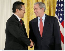 President George W. Bush shakes hands with Kay Hiramine of Colorado Springs, Colo., as he presents Hiramine with the Presidents Volunteer Service Award Thursday, May 10, 2007, in the East Room of the White House, in celebration of Asian Pacific American Heritage Month.  White House photo by Eric Draper