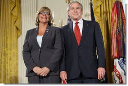 President George W. Bush joins military spouse Cindy Bjerke of Spanaway, Wash., on stage in the East Room of the White House, to receive the Presidents Volunteer Service Award Friday, May 11, 2007, during a commemoration of Military Spouse Day. White House photo by Eric Draper