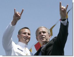 President George W. Bush and U.S. Coast Guard graduate Brian Robert Staudt offer the Texas Longhorns hand sign out to the audience following the Presidents address to the graduates Wednesday, May 23, 2007, at the U.S. Coast Guard Academy commencement in New London, Conn. White House photo by Joyce Boghosian